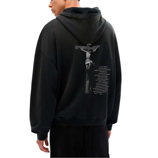 Black hoodie with a graphic design on the back of Jesus on the cross with prayer while in front of a crucifix. Catholic Clothing on model